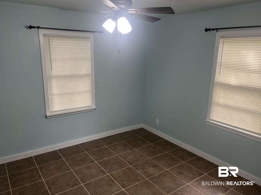 609 East Orange Avenue Foley, AL 36535 - Photo 4 of 6 Spare room with dark tile patterned floors and ceiling fan