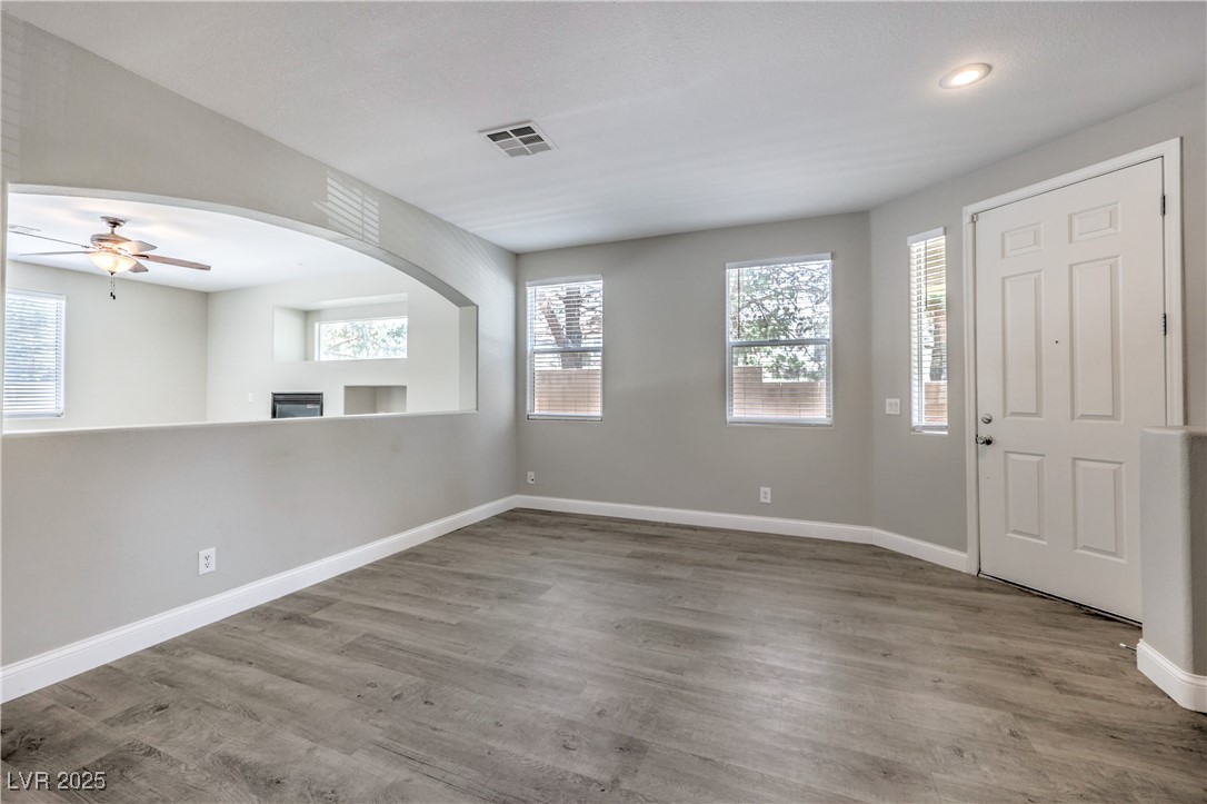 Foyer entrance with ceiling fan, wood finished floors, arched walkways, a glass covered fireplace, and recessed lighting