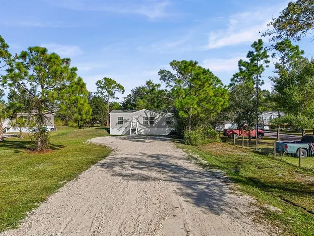 a front view of a house with a yard and a large tree