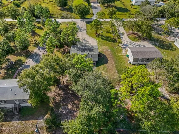 an aerial view of residential house with outdoor space and trees all around