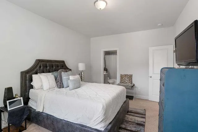 a bedroom with a bed and flat tv screen on the dresser