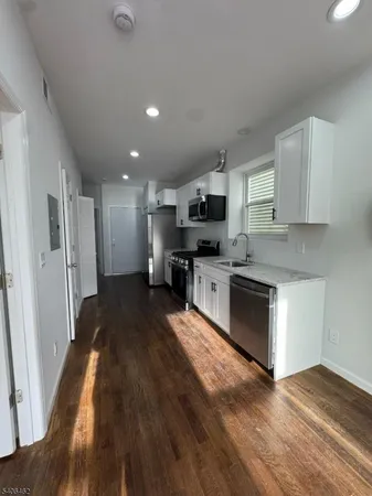 a large kitchen with cabinets wooden floor and stainless steel appliances