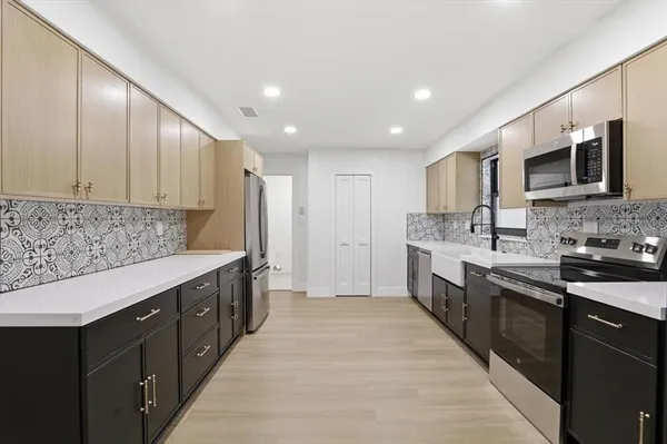 a large kitchen with stainless steel appliances kitchen island granite countertop a sink and cabinets