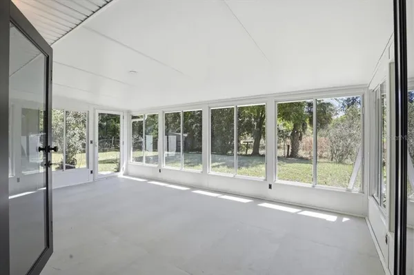 a view of an empty room with wooden floor and windows