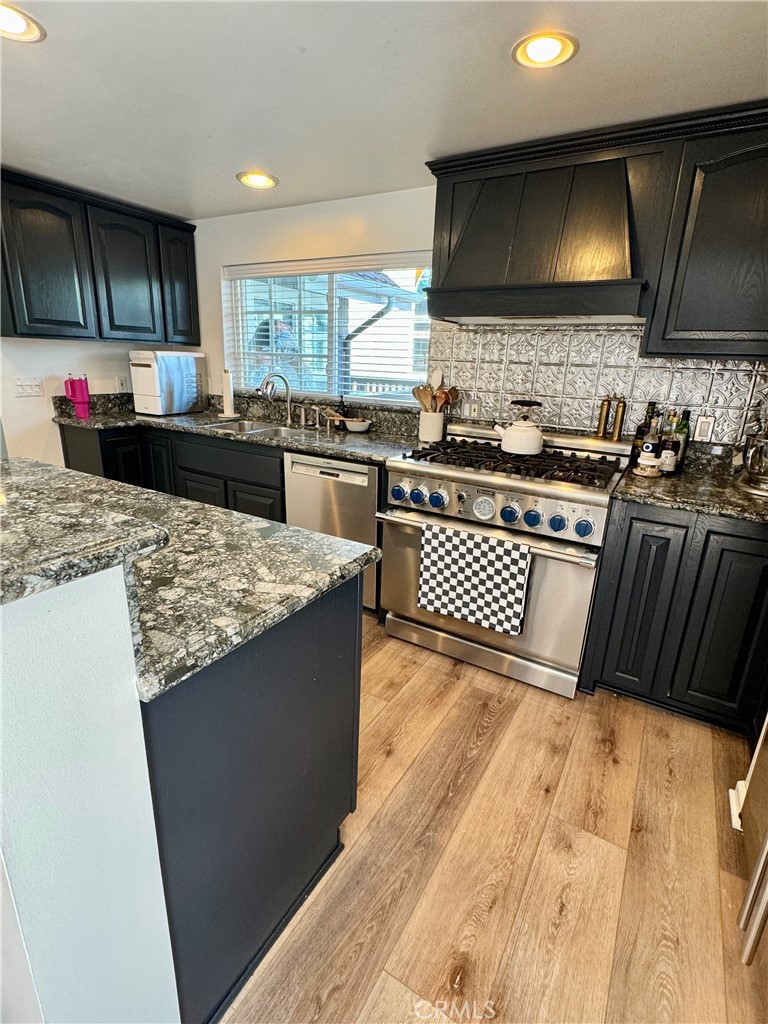 437 Cypress Drive, Unit B Laguna Beach, CA 92651 - Photo 10 of 20 a kitchen with kitchen island granite countertop a sink and a stove top oven with wooden floor
