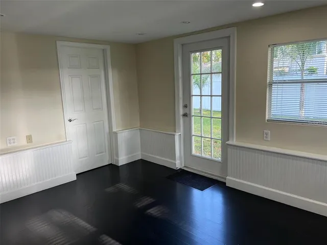 an empty room with wooden floor and windows with curtains