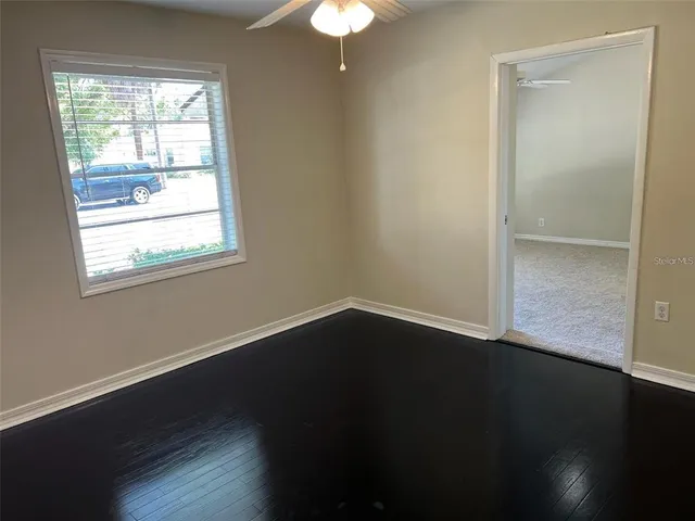 a view of an empty room with wooden floor and a window