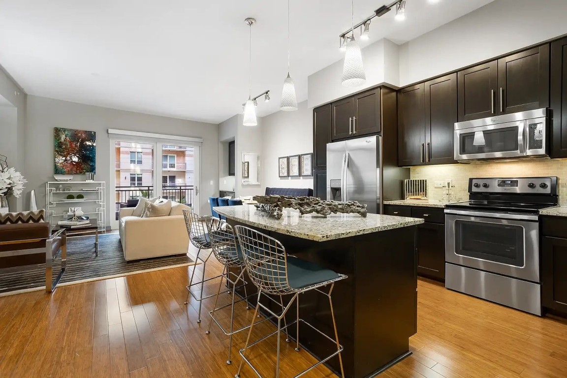 2724 Kipling Street, Unit 308 Houston, TX 77098 - Photo 27 of 29 a kitchen with granite countertop a stove a kitchen island with a dining table and chairs