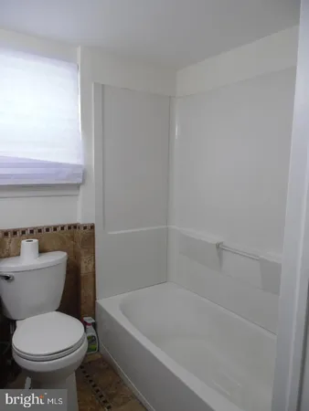 a white toilet sitting next to a bath tub
