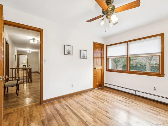 a view of empty room with wooden floor and fan