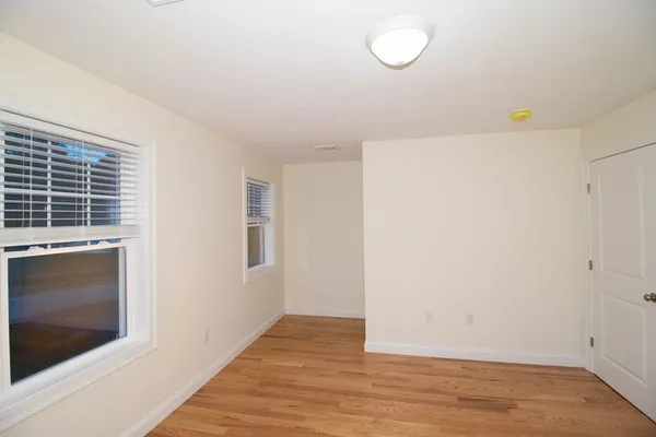a view of an empty room with wooden floor and a fireplace