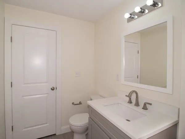 a bathroom with a toilet a sink a vanity and mirror