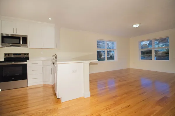 a view of a kitchen with wooden floor and electronic appliances