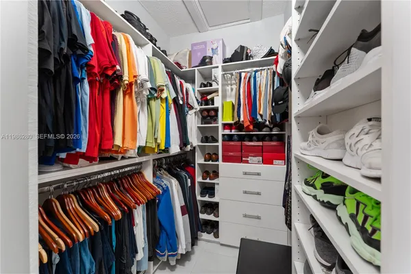 a view of walk in closet with clothes and shoes