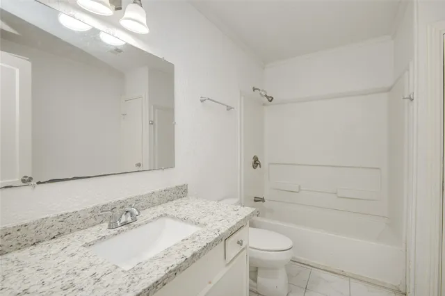 a bathroom with a granite countertop sink a toilet and shower
