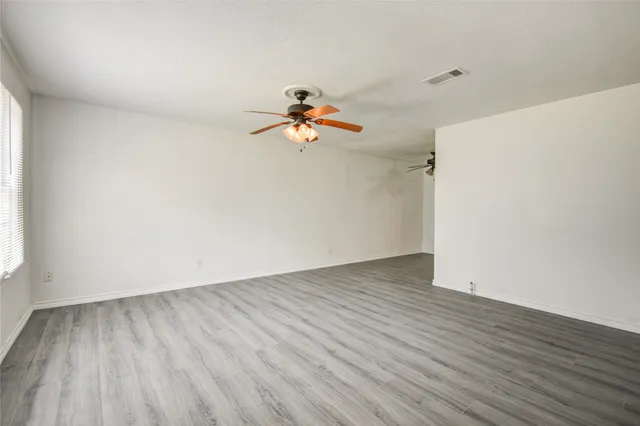 a view of a room with wooden floor and a ceiling fan