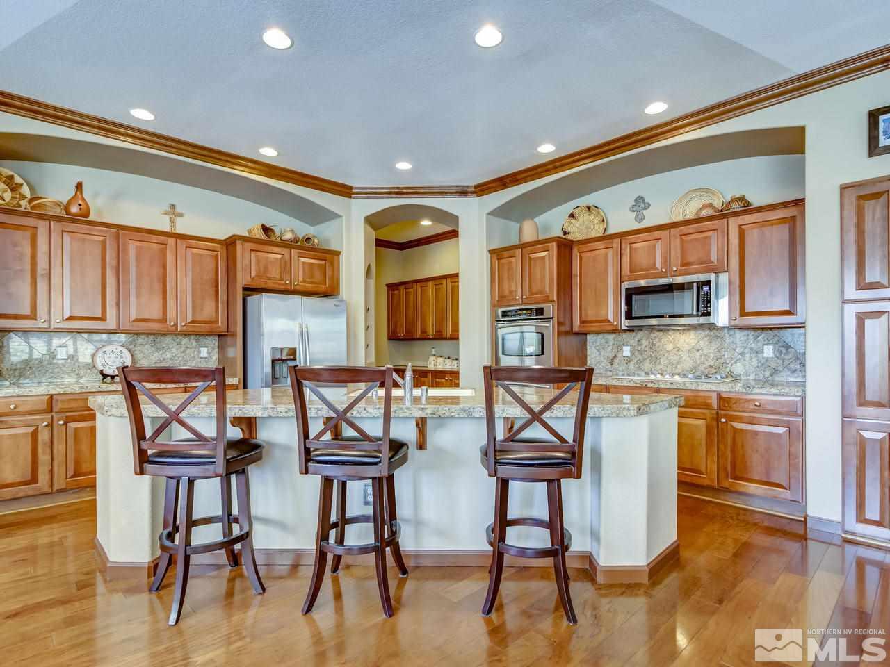 1695 Crater Court Reno, NV 89521 - Photo 9 of 25 a kitchen with stainless steel appliances granite countertop table chairs and wooden floor