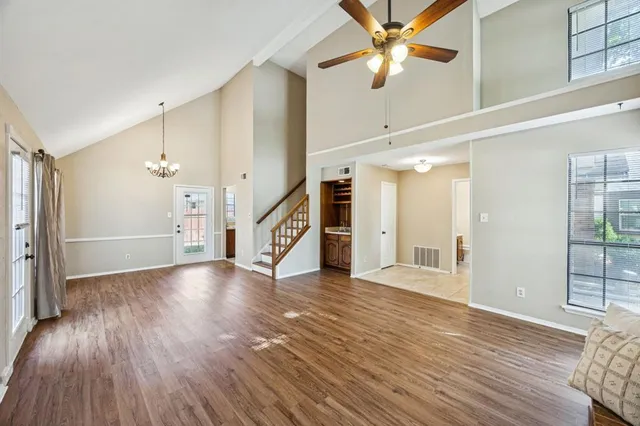 a view of a livingroom with wooden floor a ceiling fan and windows