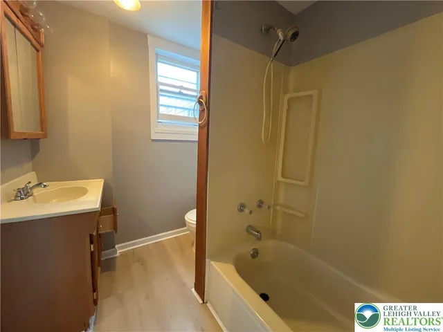 a bathroom with a tub shower sink and vanity