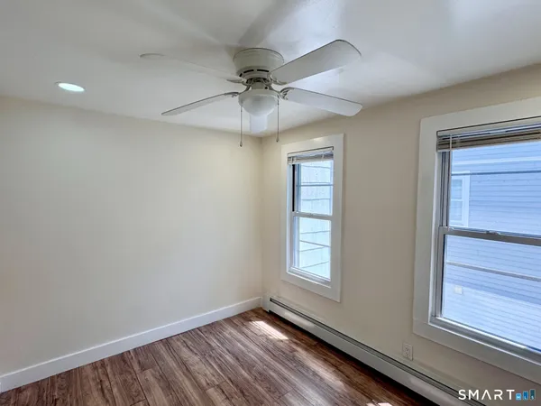 a view of an empty room with a window and wooden floor