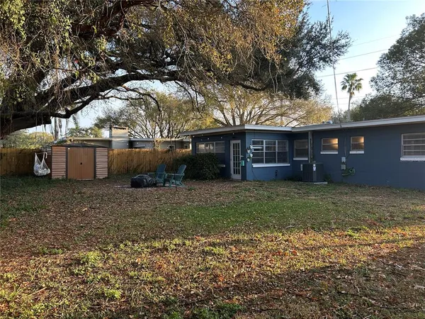 a view of a house with a yard and a large tree