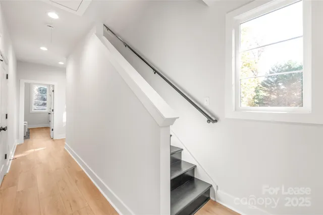a view of a hallway with wooden floor and staircase