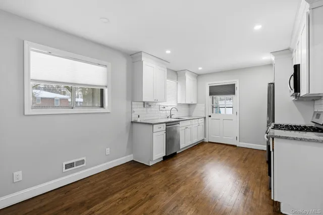 a kitchen with wooden floors and white cabinets