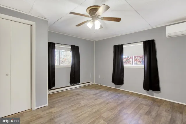 an empty room with wooden floor and ceiling fan