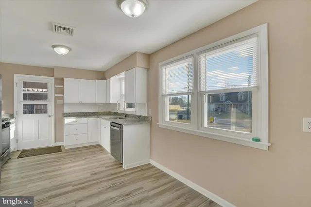 a kitchen with granite countertop white cabinets and wooden floor