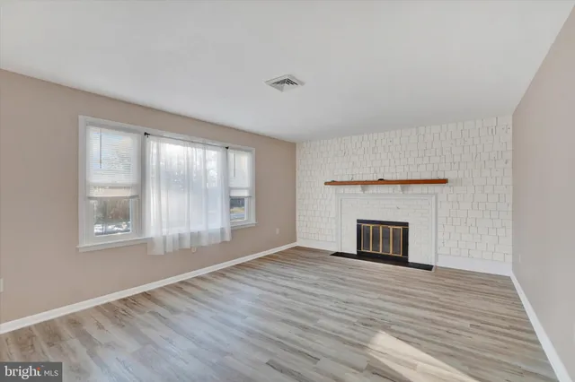 wooden floor fireplace and windows in an empty room
