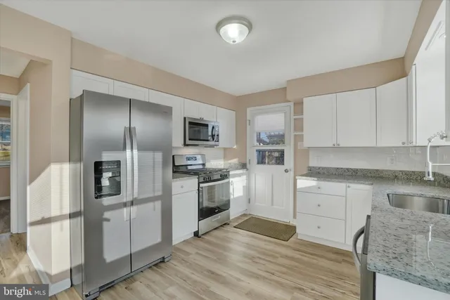 a kitchen with stainless steel appliances granite countertop a refrigerator and a stove top oven