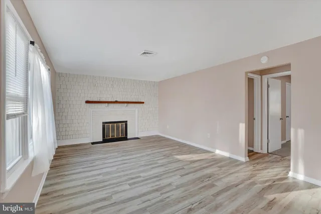 a view of empty room with wooden floor and fireplace