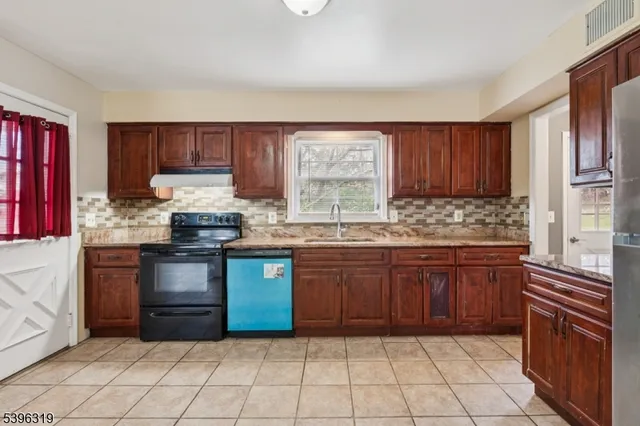 a kitchen with granite countertop a stove sink and cabinets
