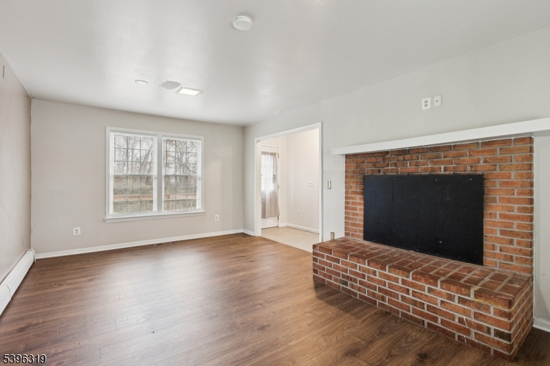 110 Old Turnpike Road Califon, NJ 07830 - Photo 6 of 25 an empty room with wooden floor fireplace and windows
