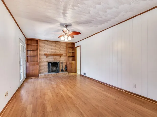 a view of an empty room with a fireplace and a window