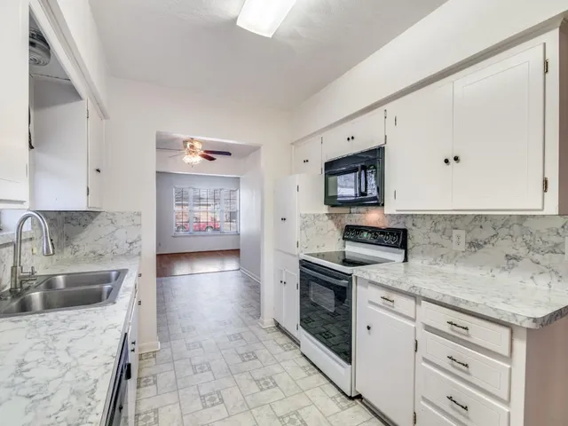 a kitchen with granite countertop a sink stainless steel appliances and cabinets