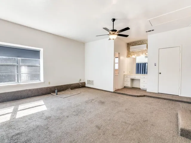 an empty room with windows and a ceiling fan