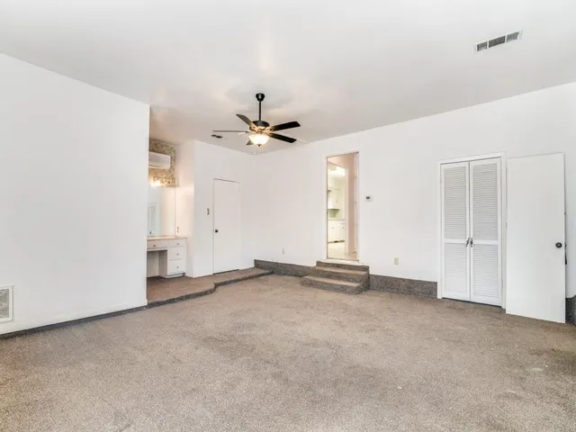 a view of an empty room with chandelier fan