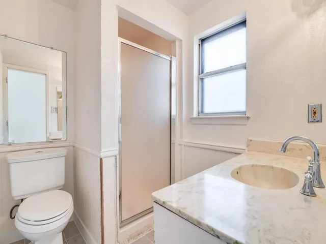 a bathroom with a granite countertop sink a toilet and a mirror