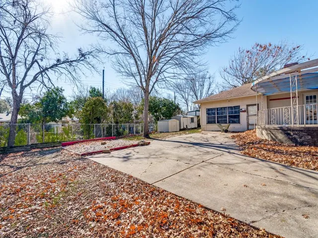 a view of a white house with a large tree with yard