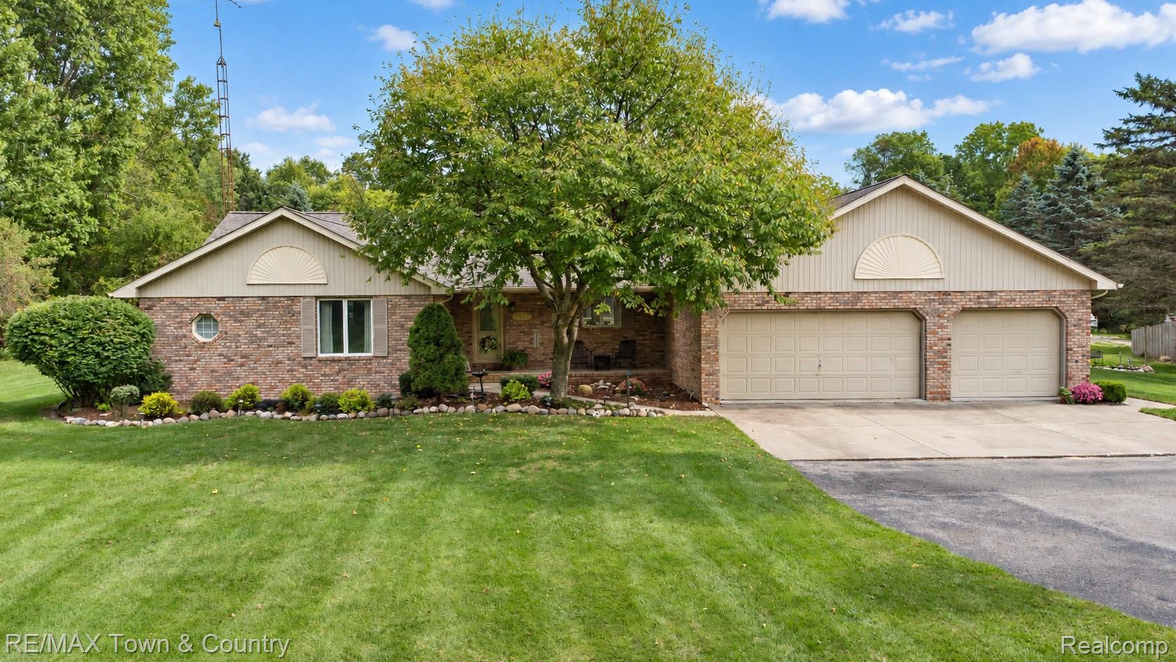 5464 North Seymour Road Flushing, MI 48433 - Photo 1 of 45 Brick exterior with a prominent two-car garage, mature landscaping, and a well-maintained lawn
