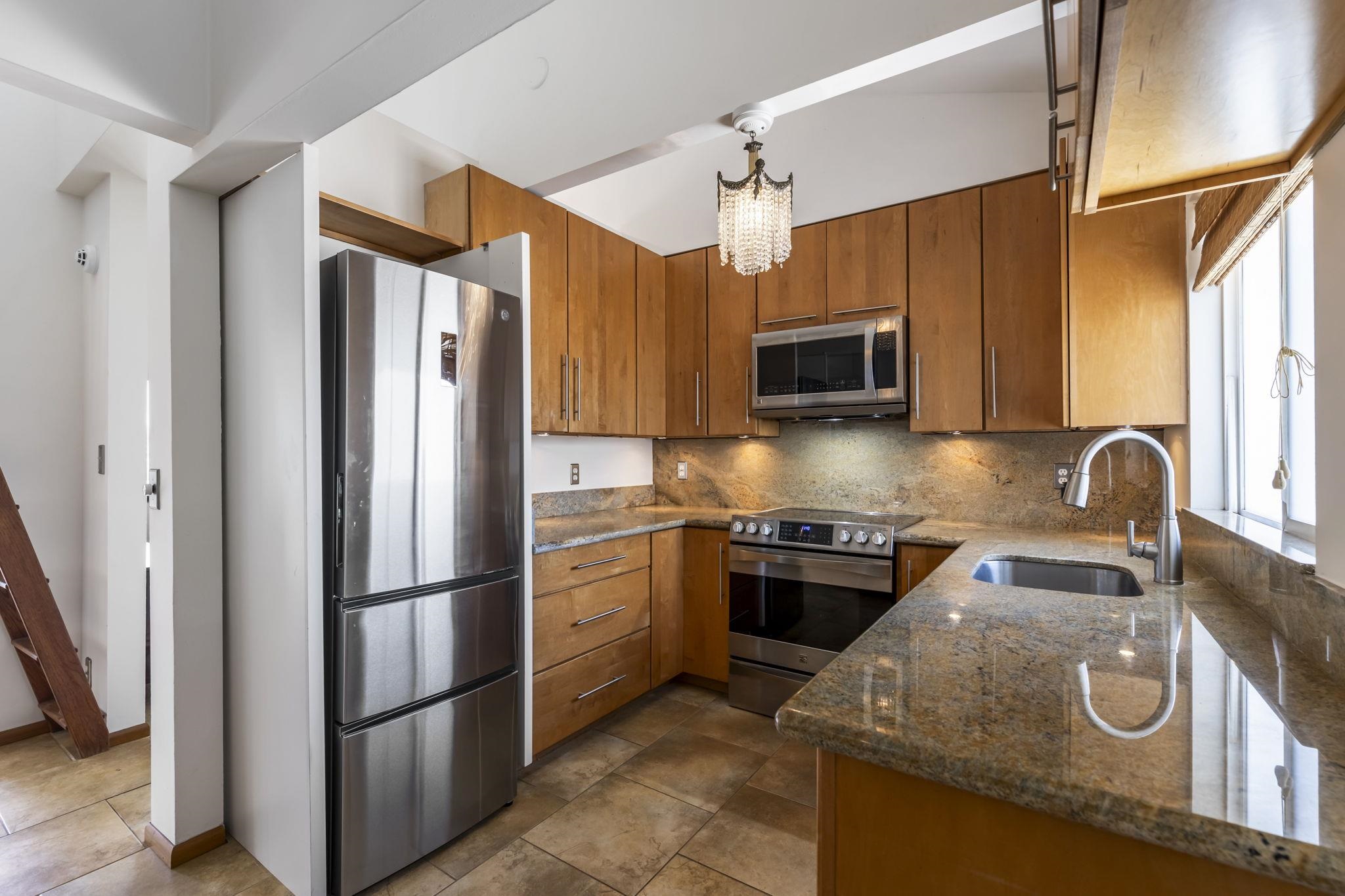 2670 Kanakanui Road Kihei, HI 96753 - Photo 8 of 41 a kitchen with granite countertop stainless steel appliances and wooden cabinets