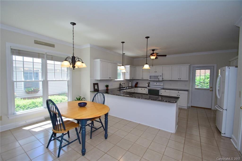 229 Kimberly Road Davidson, NC 28036 - Photo 7 of 23 a kitchen with stainless steel appliances kitchen island granite countertop a table chairs in it and wooden floors