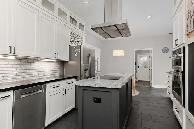 a kitchen with granite countertop a sink a refrigerator a stove and cabinets