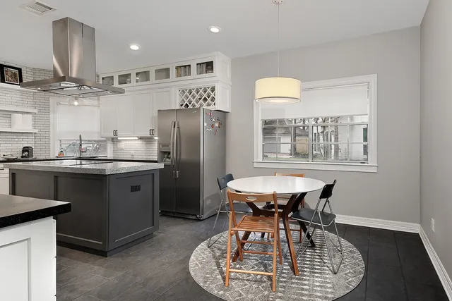 a kitchen with stainless steel appliances granite countertop a table chairs and a refrigerator