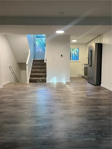 a view of an empty room with wooden floor and stairs