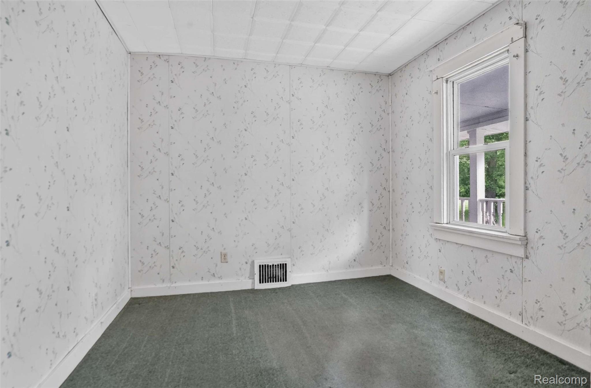 1437 East Cook Road Grand Blanc, MI 48439 - Photo 40 of 69 Room featuring patterned wall paneling, a single window with white trim, a floor-mounted vent, and green carpeting