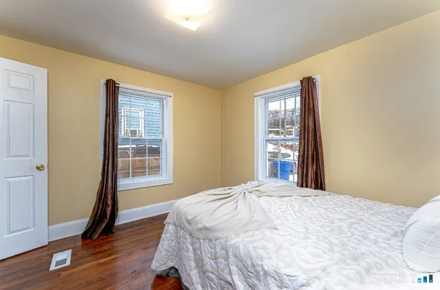 a bedroom with a bed wooden floor and windows