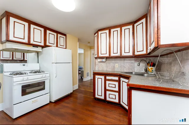 a kitchen with stainless steel appliances granite countertop a refrigerator a stove and a sink with large cabinets