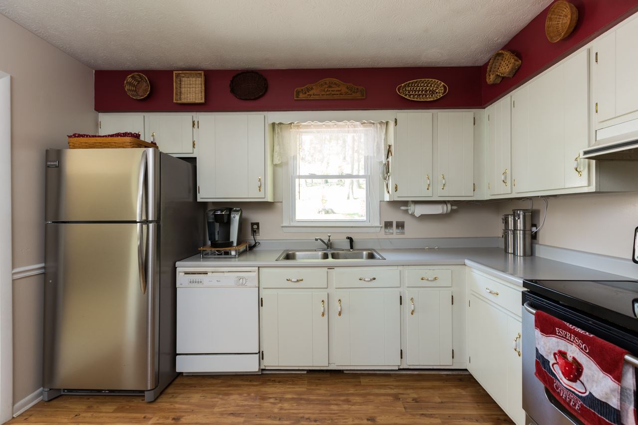 Bright and welcoming kitchen with painted wood cabinets, formica counters, updated stainless appliances, and a pantry.